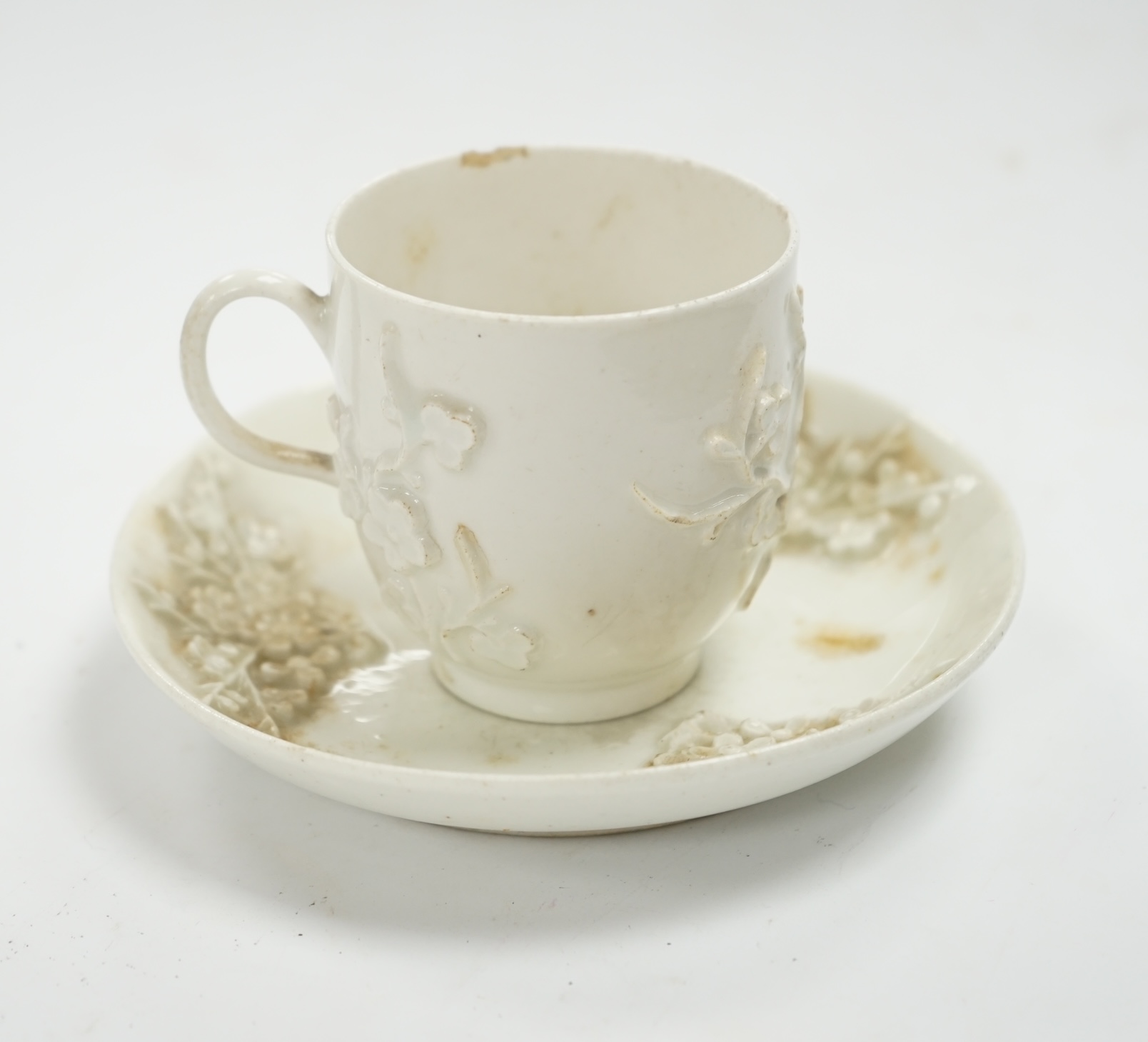 A Bow prunus sprigged coffee cup and saucer, c.1760, saucer 11.5cm diameter, cup 6cm high. Condition - cup has a chip to the rim and both saucer and cup interior have wear to glazing